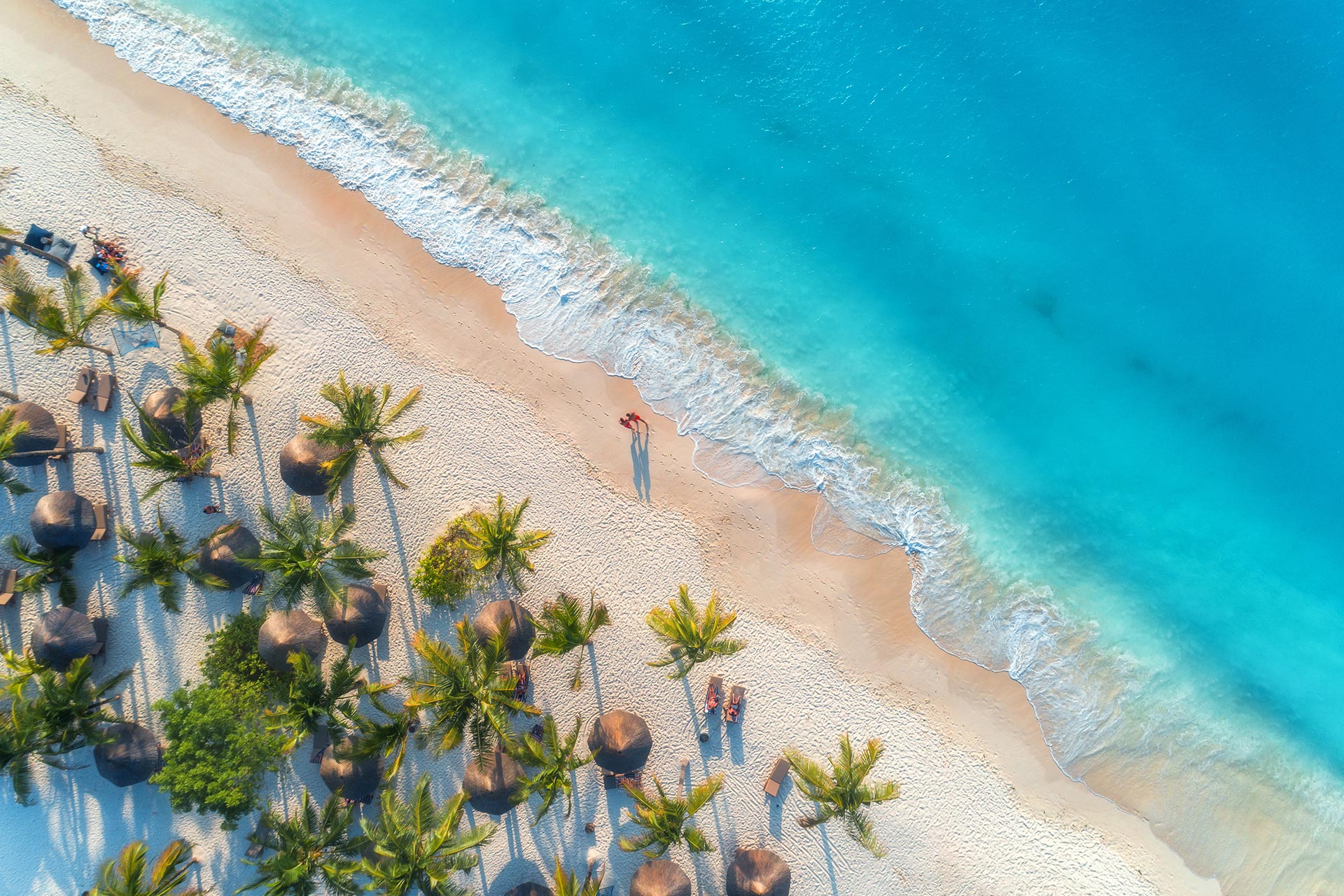 aerial-view-of-umbrellas-blue-sea-with-waves-at-sunset-summer-holiday-in-zanzibar-africa-AdobeStock_257256915 Add a beach holiday in Zanzibar to your itinerary